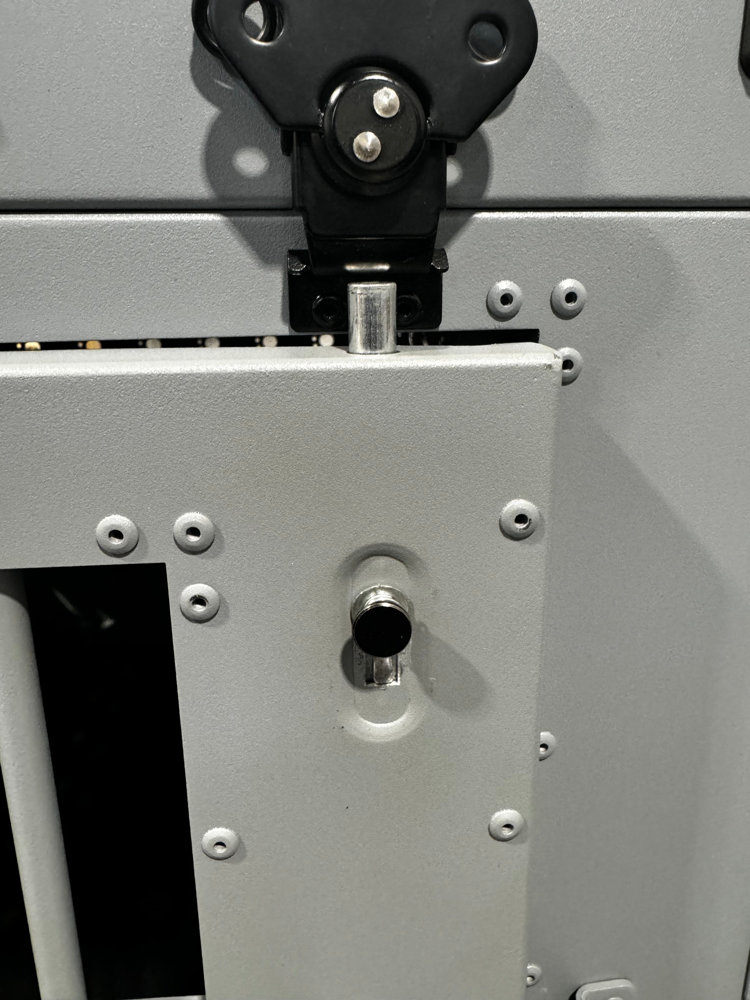 Medium grey K&J crate in an industrial building, close-up of the new internal door deadbolt extended, demonstrating how it secures into the door frame.  the door slightly open.