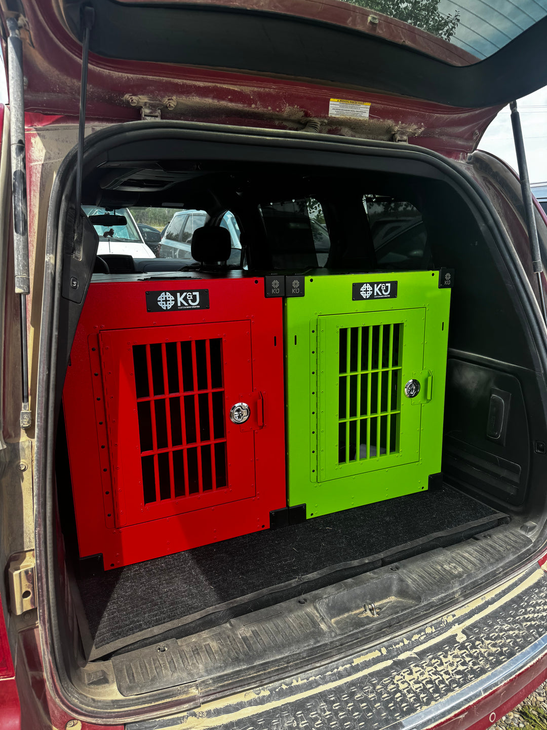 Open trunk of a Toyota passenger van with two stationary K&J crates securely strapped down—one in lime green and the other in red.